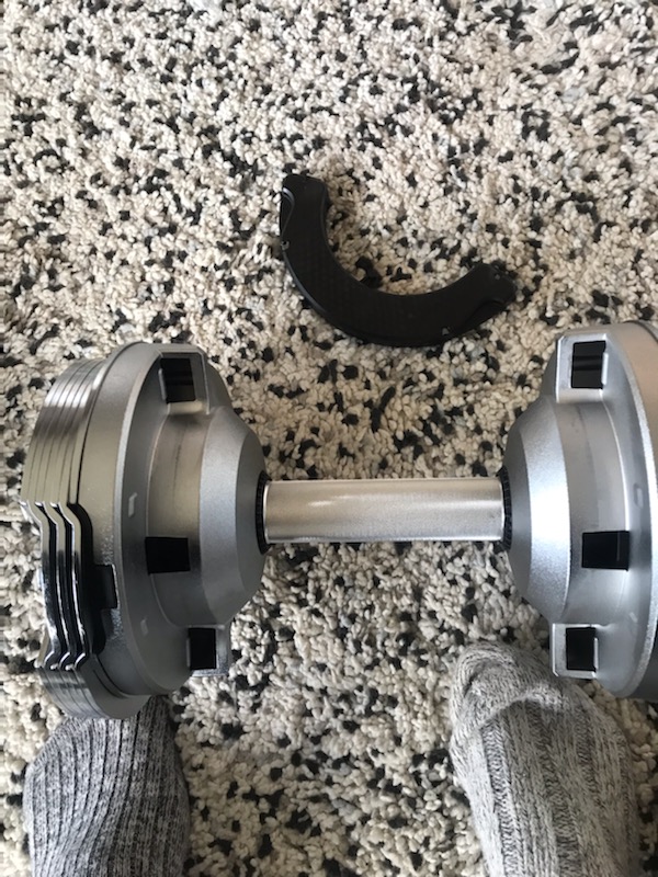 braingain adjustable dumbbells resting on their cradles on a wooden floor